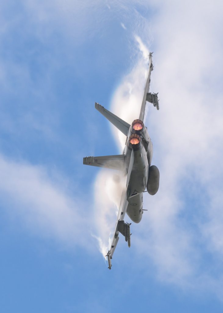 Boeing F/A-18F Super Hornet A44-221 of 1SQN RAAF performing its flying display at TAVAS GWFD 2018. Afterburners are lit and condensation sheets are forming on wing leading edges.