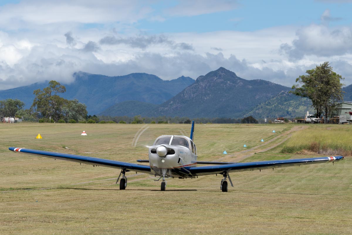 Piper PA-32R-301 Saratoga SP VH-NED taxiing at the Airsport Qld breakfast fly-in with a scenic mountain backdrop.